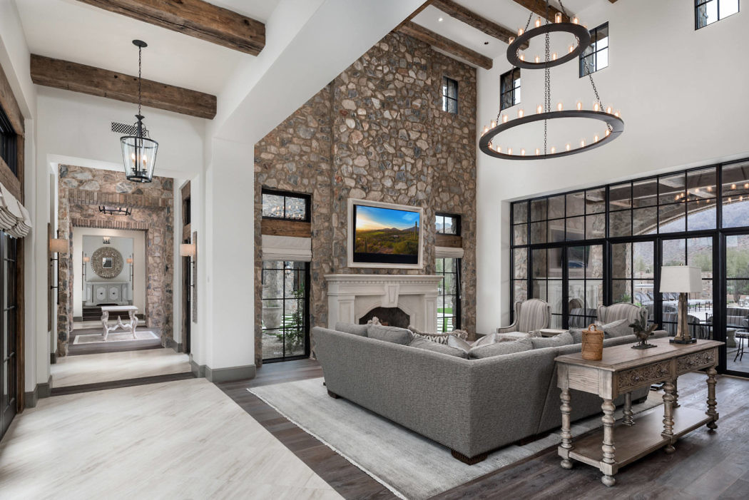 Luxurious living room with stone fireplace, beamed ceiling, and elegant furnishings.