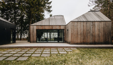 Contemporary wooden structures with gabled roofs and large glass doors.