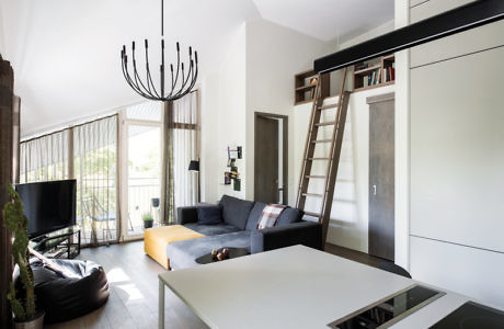 Modern living room with couch, chandelier, and loft ladder.