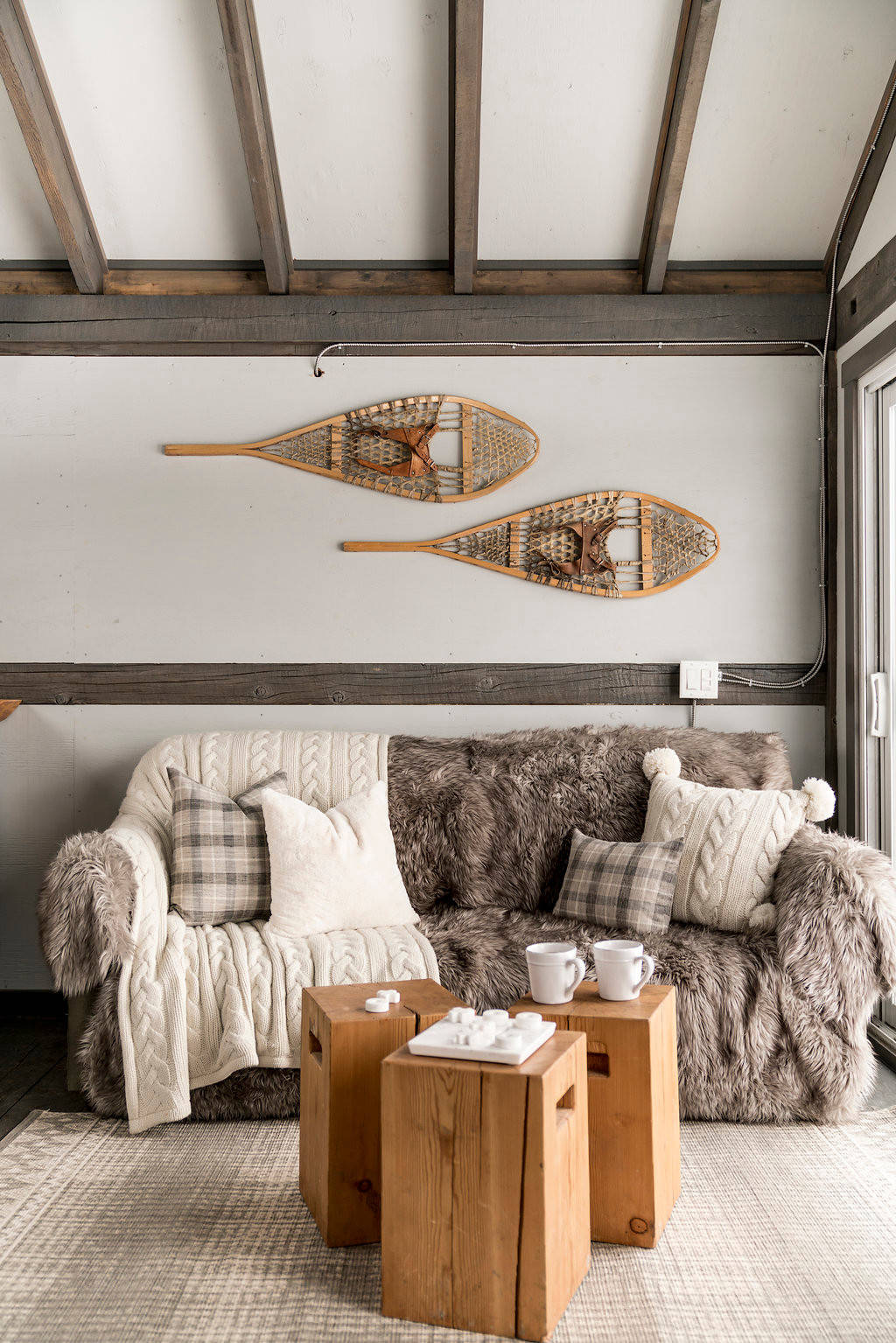 Cozy interior with plush sofa, wooden side tables, and snowshoes on
