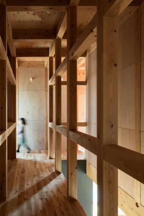 Wooden interior hallway with vertical columns and a blurred person walking.