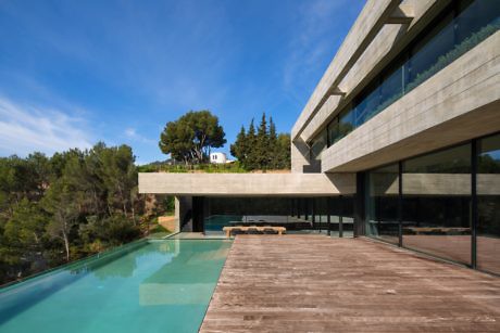 Contemporary house with large glass windows, an overhanging terrace, and a