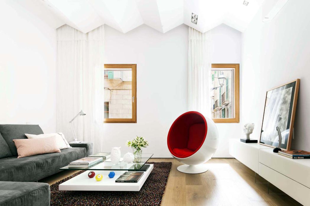 Modern living room with white walls, a red chair, and gray sofa.