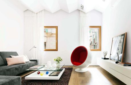 Modern living room with white walls, a red chair, and gray sofa.