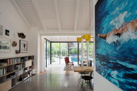 Bright, airy living space with large swimming artwork and pool view.