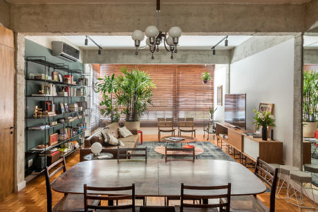 Modern living room with concrete ceiling, wooden furniture, bookshelf, and indoor plants