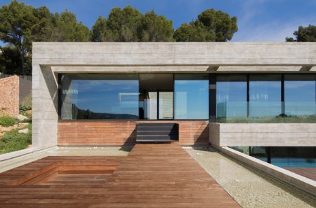 Contemporary house with large glass windows, concrete structure, and wooden deck.