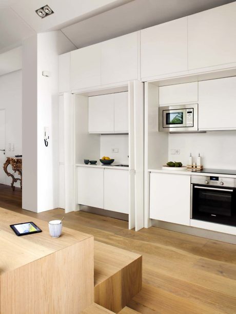Minimalist white kitchen with sleek cabinets and wooden floors.