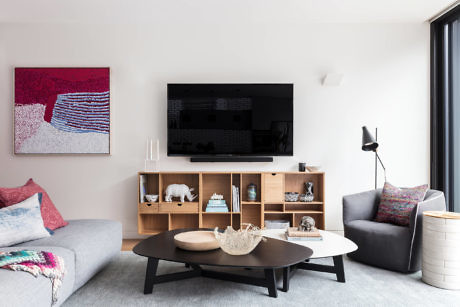 Modern living room with sofa, TV stand, coffee table, and decorative items.