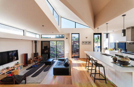 Modern living room with high ceilings, kitchen island, and large windows.