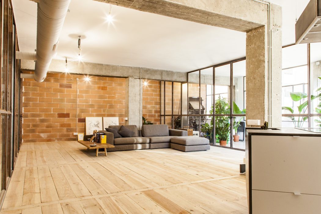 Urban loft space with exposed brick, concrete beams, and large windows.