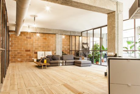 Urban loft space with exposed brick, concrete beams, and large windows.