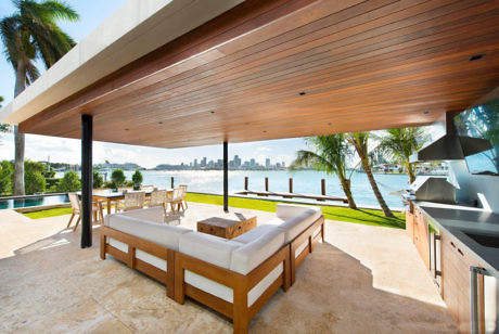 Luxurious outdoor patio with seating, BBQ, and waterfront view.