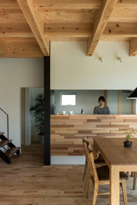 Contemporary wood-themed kitchen interior with exposed beams and a person standing.