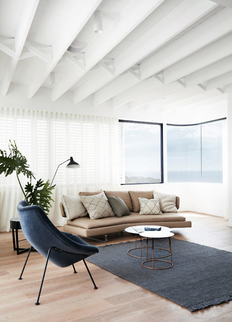 Contemporary living room with white beams, large window, and minimalist furniture.