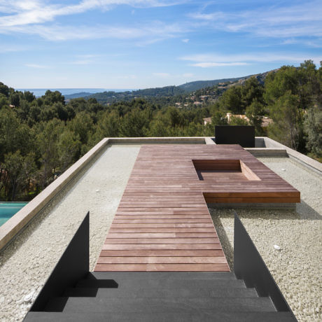 Contemporary terrace with wooden decking and infinity pool overlooking a scenic landscape.