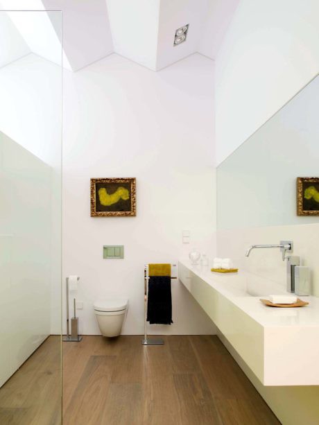 Modern bathroom with geometric ceiling, floating vanity, and mirror wall.