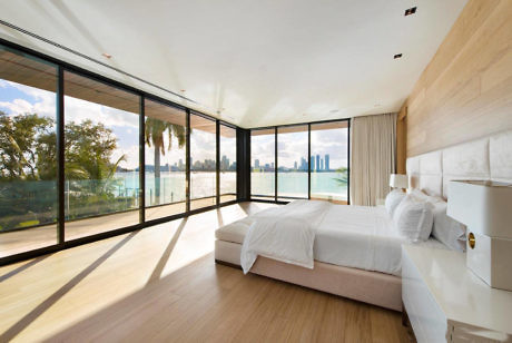 Modern bedroom with large windows overlooking a city skyline.