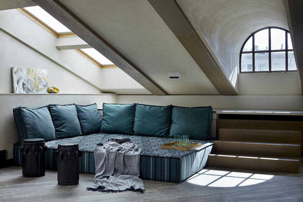 Cozy attic lounge area with L-shaped sofa, throw pillows, and skyl