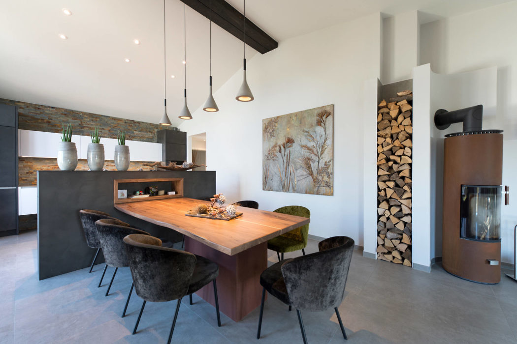 Modern kitchen with wooden table, pendant lights, and a fireplace.