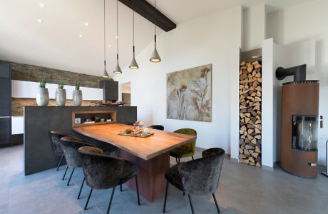 Modern kitchen with wooden table, pendant lights, and a fireplace.