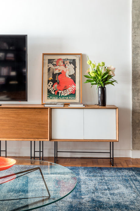 Contemporary living space with a sleek console, vintage poster, and floral arrangement.