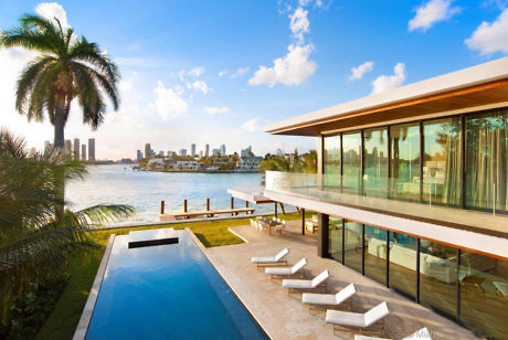 Sleek waterfront home with panoramic glass walls and infinity pool.