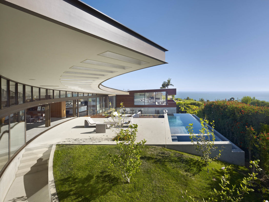 Sleek house with curving roofline, expansive terrace, and pool overlooking