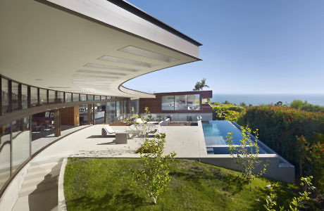 Sleek house with curving roofline, expansive terrace, and pool overlooking