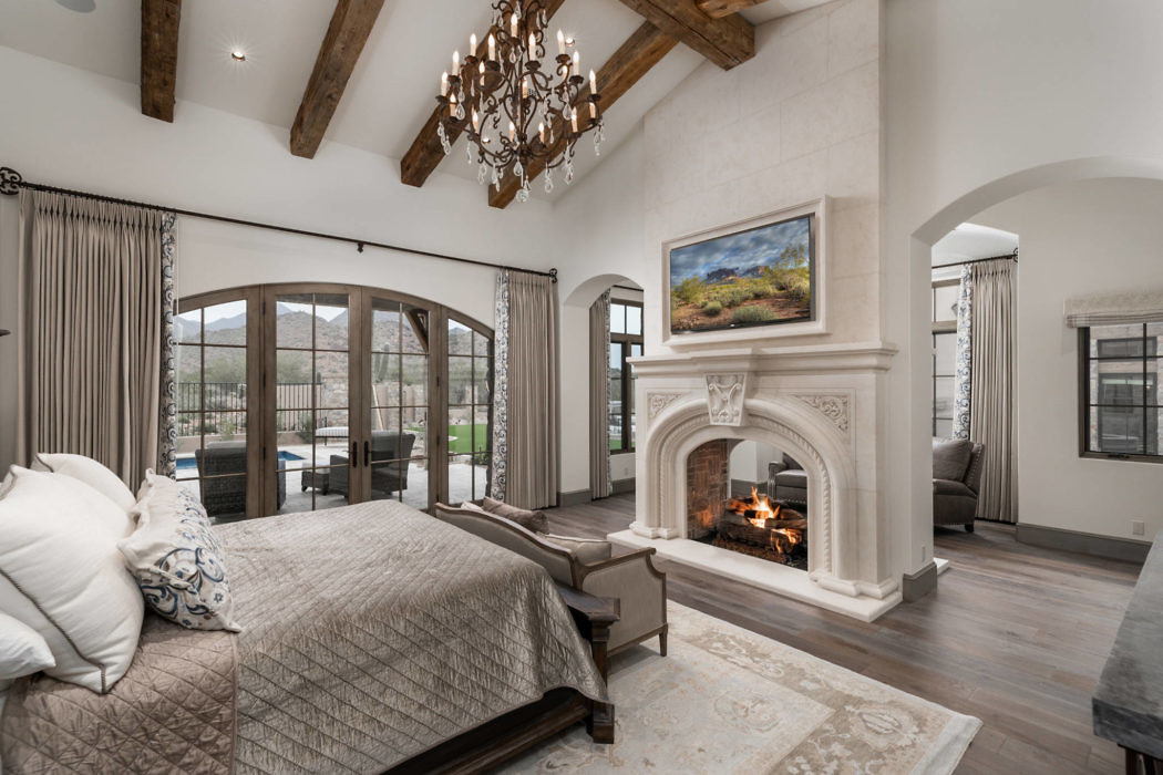 Elegant bedroom with fireplace, beamed ceiling, and French doors.