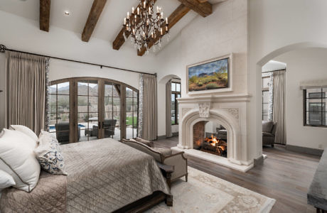 Elegant bedroom with fireplace, beamed ceiling, and French doors.