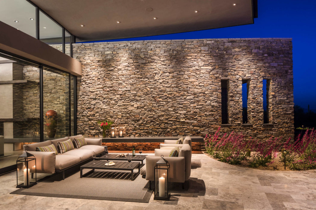 Contemporary outdoor lounge area with stone wall and sleek furniture.
