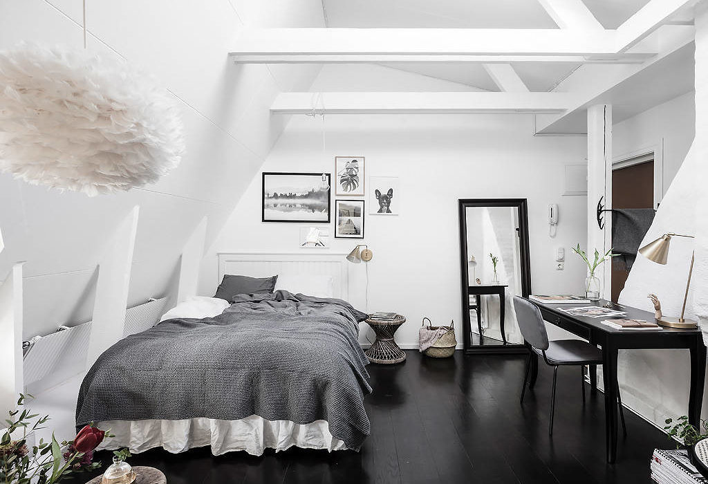 Modern monochrome bedroom with dark floor, white walls, and exposed beams.