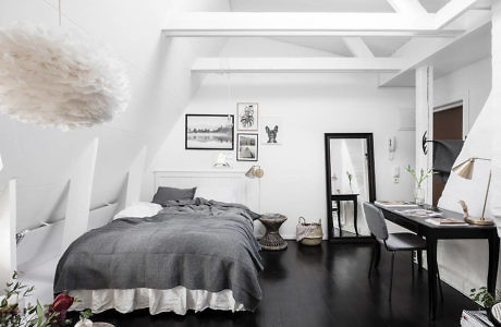 Modern monochrome bedroom with dark floor, white walls, and exposed beams.