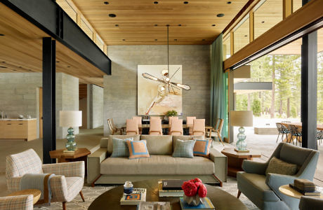 Contemporary living room with wooden ceilings, plush seating, and large windows.