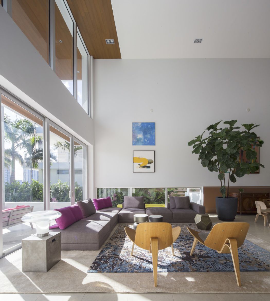 Modern living room with high ceiling, large windows, and colorful furniture.