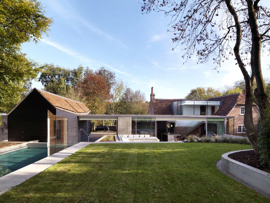 Modern house extension with glass walls overlooking a pool and garden.