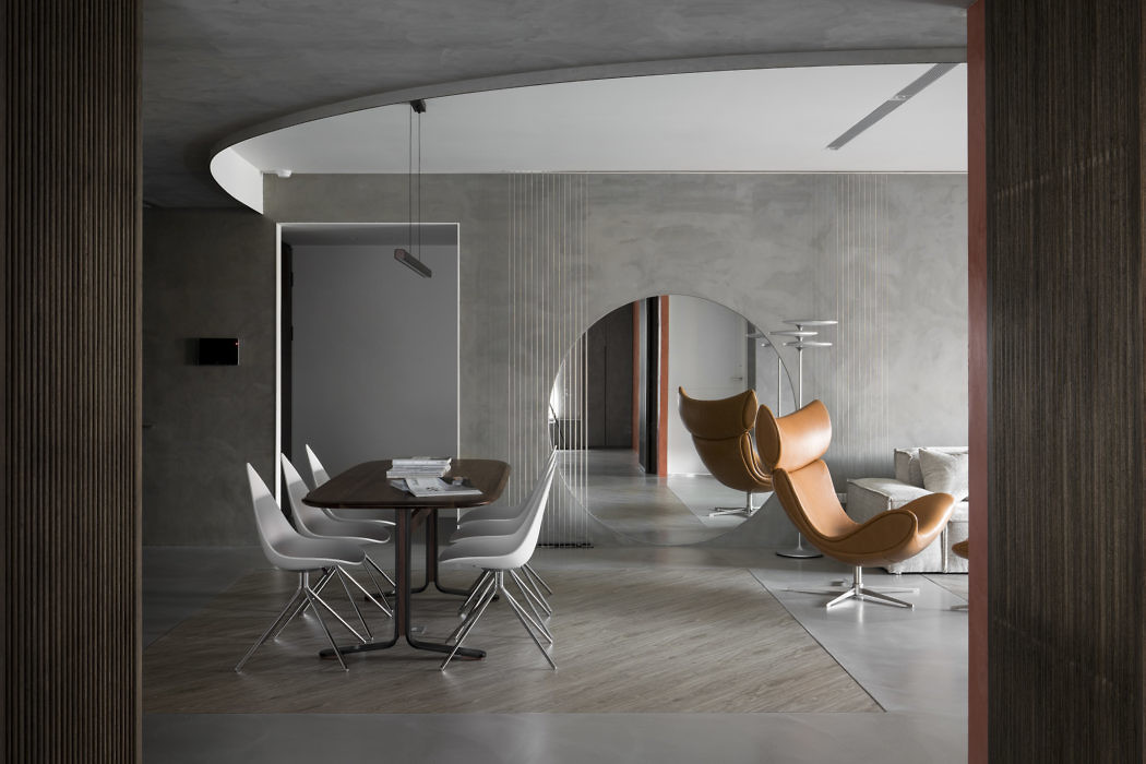 Modern interior with curved walls, a white dining set, and a brown lounge chair