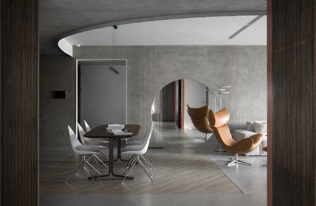 Modern interior with curved walls, a white dining set, and a brown lounge chair