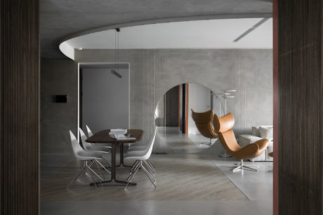 Modern interior with curved walls, a white dining set, and a brown lounge chair