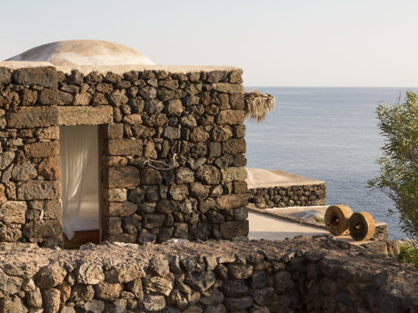 Traditional stone building by the sea with a thatched roof detail.
