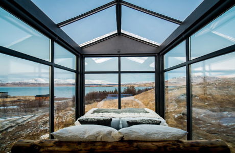 Glass-walled bedroom with panoramic nature views