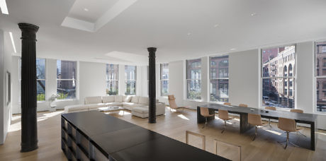 Modern minimalist living room with large windows, dining area, and black columns.