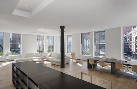 Modern minimalist living room with large windows, dining area, and black columns.