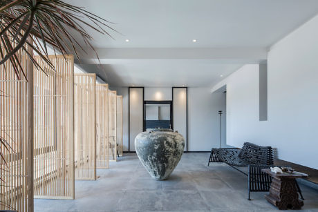 Minimalist interior with wooden slat partition and oversized vase centerpiece.