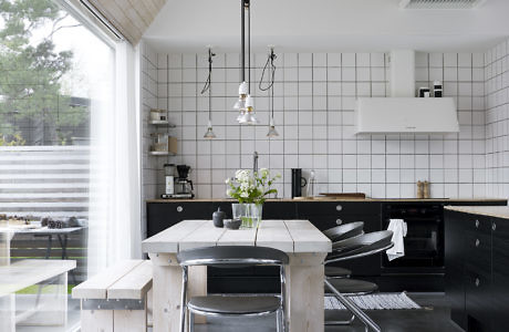 Modern kitchen interior with wood accents, high ceiling, and black cabinets.