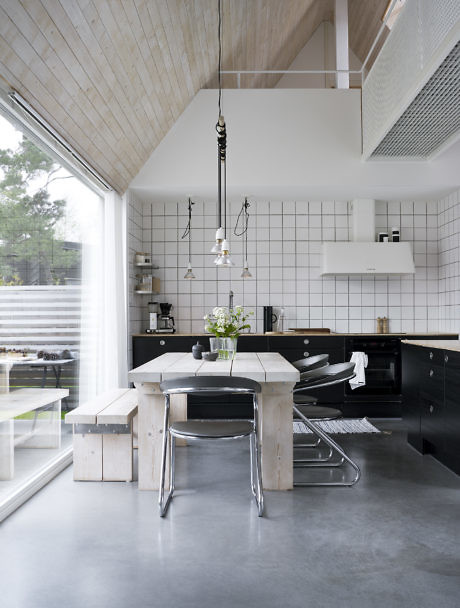 Modern kitchen interior with wood accents, high ceiling, and black cabinets.