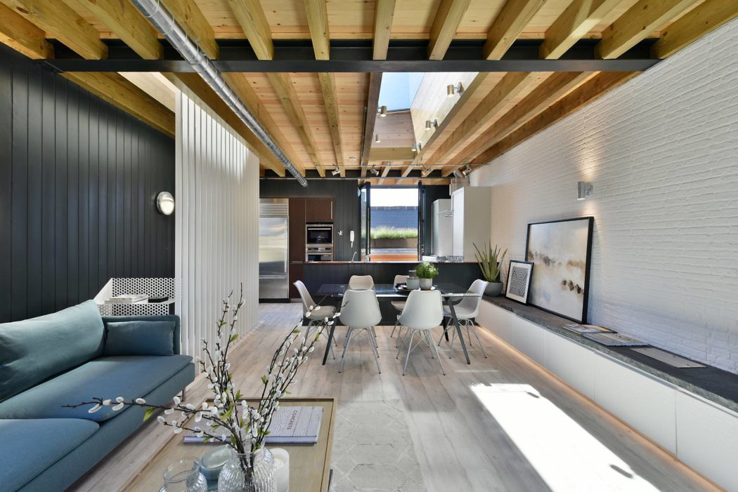 Contemporary open-plan living space with exposed wooden beams and minimalist decor.