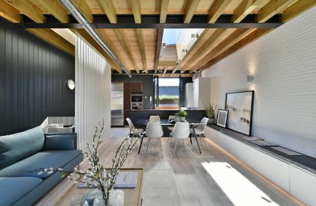 Contemporary open-plan living space with exposed wooden beams and minimalist decor.