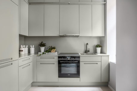 Modern kitchen with white cabinets, built-in appliances, and plant decor.